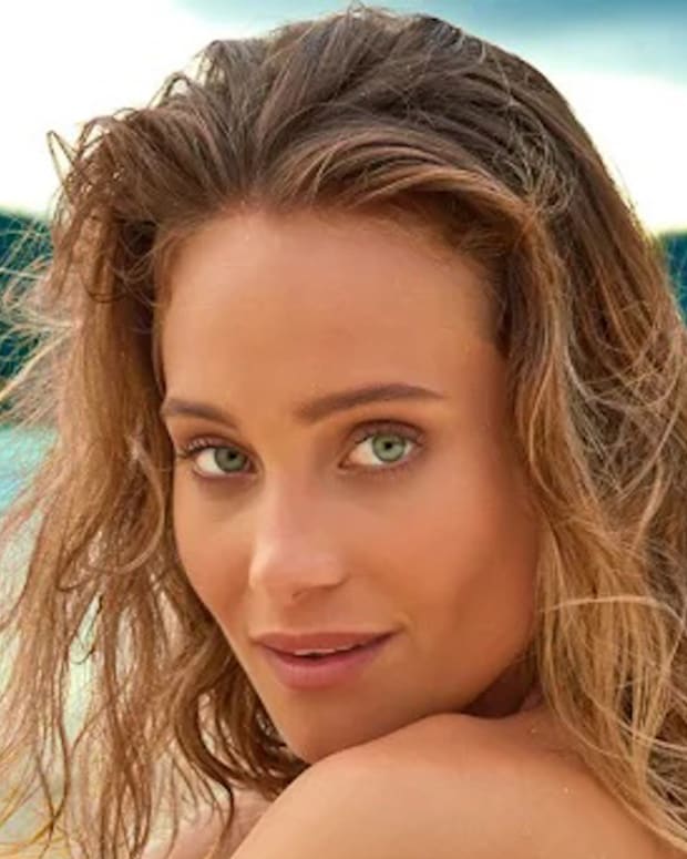 Hannah Jeter sits on the beach and looks to her side at the camera.